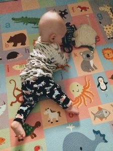 prone baby with blurred head moves toward two toys in front of her